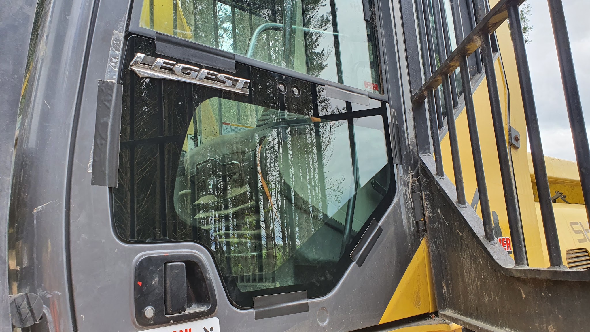 Glass fitted to the cab of a yellow heavy machine