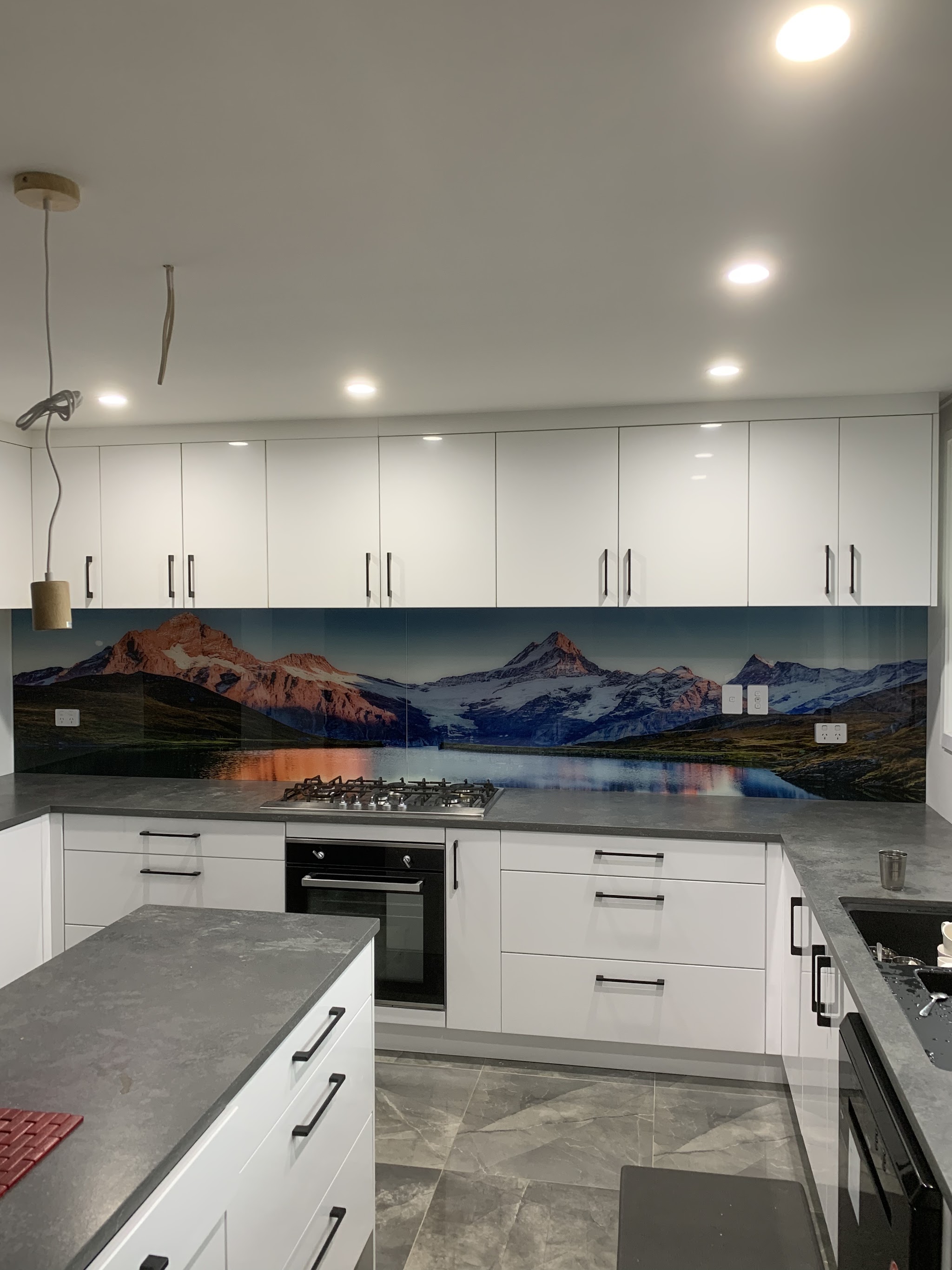 Kitchen with a glass splashback printed with a mountain lake scene